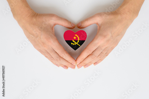 The national flag of Angola in female hands. The concept of respect and solidarity with the citizens of Angola.