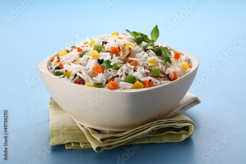 Indian veg biryani, veg pulav, Indian vegetable pulav, Biriyani, vegetable Biriyani served in a ceramic bowl on blue background