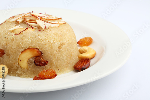 Indian gujrati or maharashtrian or south indian sweet dish SUJI Halwa or sheera or KESARI, famous sweet food in india, also known as halwa, served in white ceramic plate, garnished with dry fruits photo