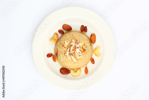 Indian gujrati or maharashtrian or south indian sweet dish SUJI Halwa or sheera or KESARI, famous sweet food in india, also known as halwa, served in white ceramic plate, garnished with dry fruits photo