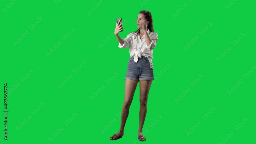 Young attractive summer woman in stylish clothes taking selfies with smartphone. Full body isolated on green screen background Young attractive summer woman in stylish clothes taking selfies with smartphone. Full body isolated on green screen background