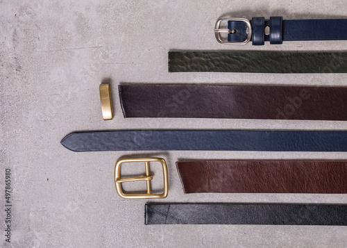 close up of leather belts on gray background. Ends of smooth leather belts with classic buckle.
