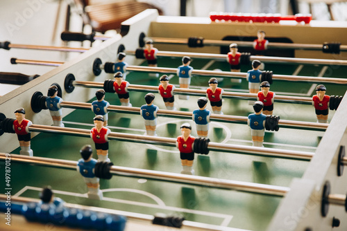 A game. Table football, figurines of football players in red and blue on a green stadium