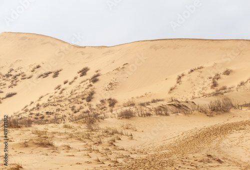 Sarykum dune. Dagestan  Russia. A unique sandy mountain in the Caucasus on a cloudy day. Grass grows on a sand dune.