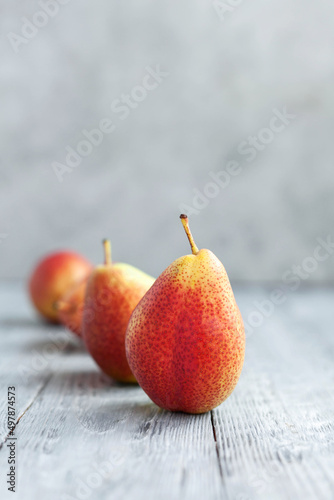 Ripe red pears lined up in a row on wooden table
