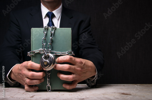 Businessmann hält ein geheimes, in Ketten und mit einem Vorhängeschloss verschlossenes Buch in seinen Händen photo