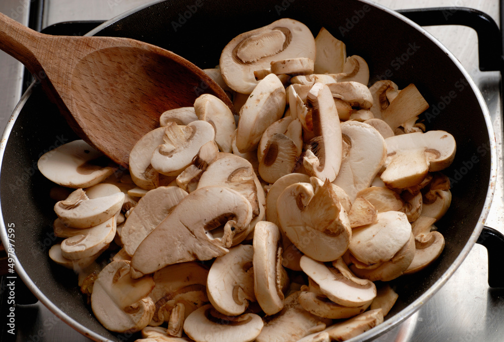 Cooking champignon fungus on cookin pan and wood spoon Cooking champignon fungus on cookin pan and wood spoon