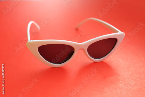 Stylish white glasses on a red background