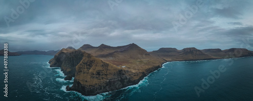 Flying a drone high above the Atlantic Ocean to capture the enormous cliffs of the Faroe Islands at Nordradalur. Streymoy island, november 2021. Panoramic view photo