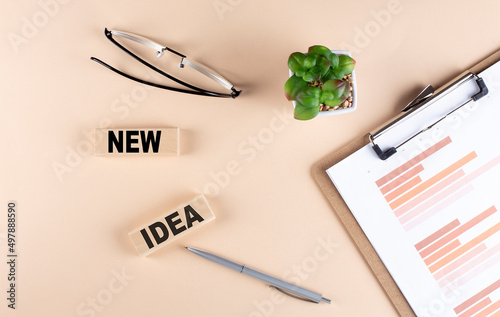 NEW IDEA text on wooden block with chart and glasses, business concept