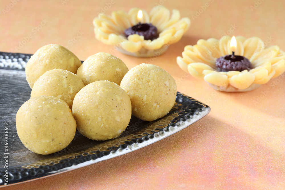 Diwali Sweets besan Laddu Indian traditional sweet served in a decorative silver plate along with lamps or candles Diwali Sweets besan Laddu Indian traditional sweet served in a decorative silver plate along with lamps or candles
