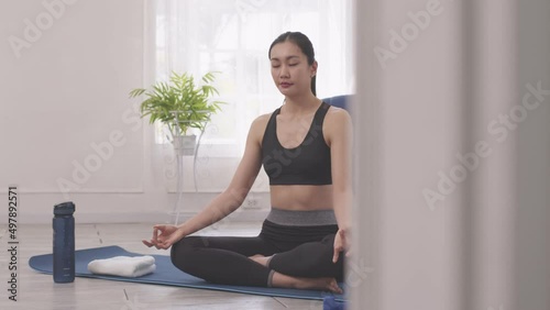 Asian  woman does morning yoga, sitting in Easy position, Sukhasana posture, and meditating. photo