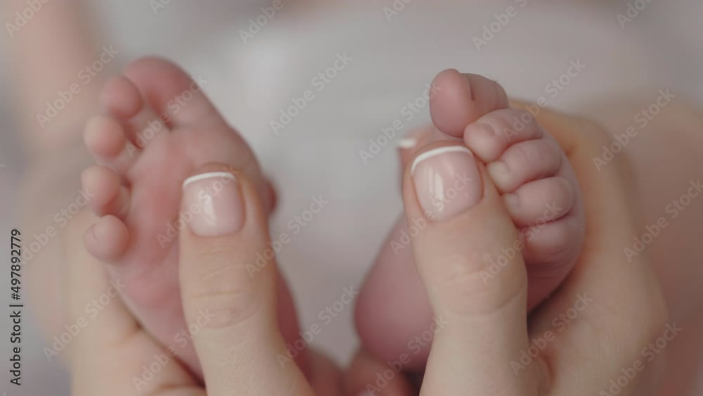 Close up of woman gently massaging feet for her little baby Close up of woman gently massaging feet for her little baby
