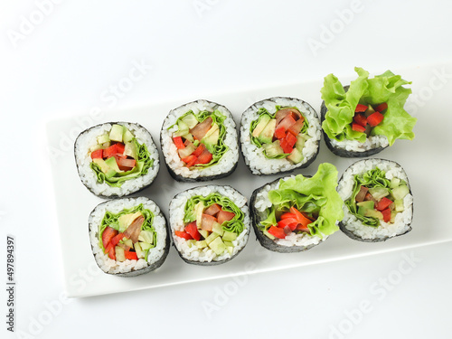 vegetable vegetarian sushi roll with vegetables in nori on a white plate isolated