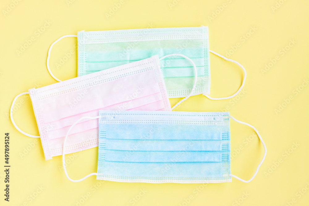 Multicolored surgical masks on yellow background Multicolored surgical masks on yellow background