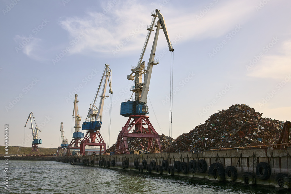 Empty pier in port with tower cranes and big heap of scrap metal