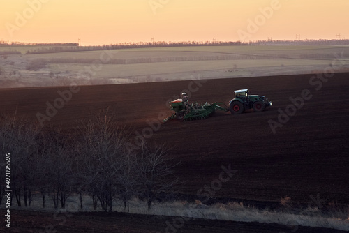 Tractor plows agricultural field at sunset in the fall