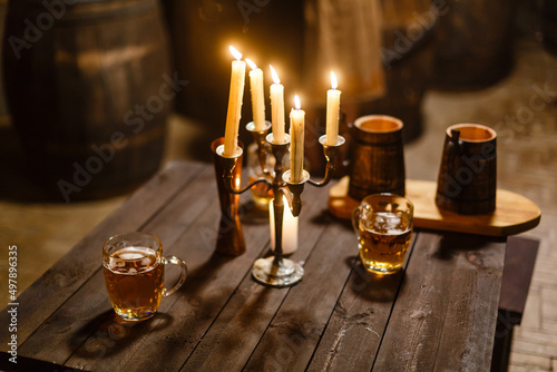 A glass of beer next to a candle on a table