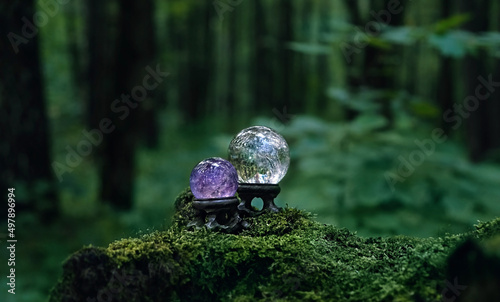 crystal balls of clear quartz and amethyst in mysterious forest, natural dark green background. quartz balls for Magic Crystal Ritual, Witchcraft, spiritual esoteric practice. Harmony, life balance