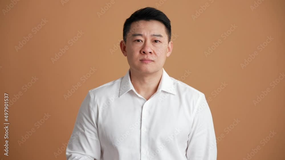 Pensive Asian businessman giving negative answer in the orange studio Pensive Asian businessman giving negative answer in the orange studio