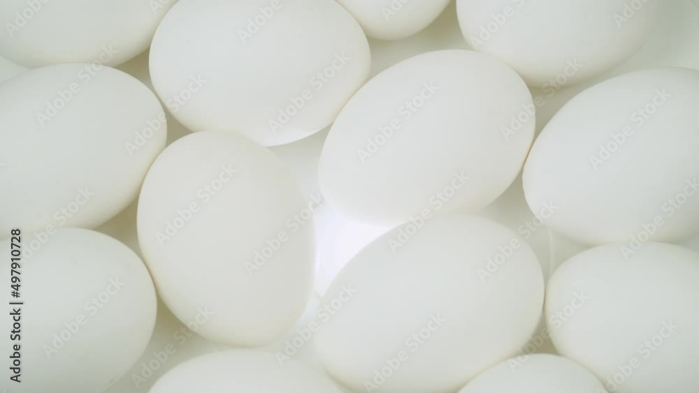 Raw eggs on a white backlit platform. White chicken eggs in turn top view Raw eggs on a white backlit platform. White chicken eggs in turn top view