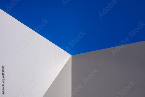 Sunlight and shadow on surface of white cement wall in perspective view against blue clear sky, architecture background design concept
