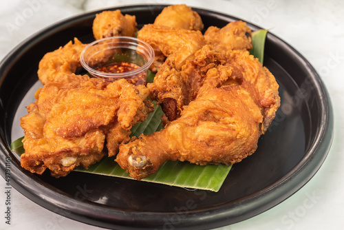 Obraz na plátně Appetizing fried chicken that sits on a banana leaf in a black plate