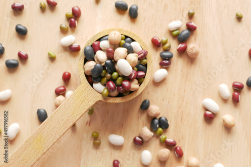 close up of mixed beans in a wooden spoon on table 