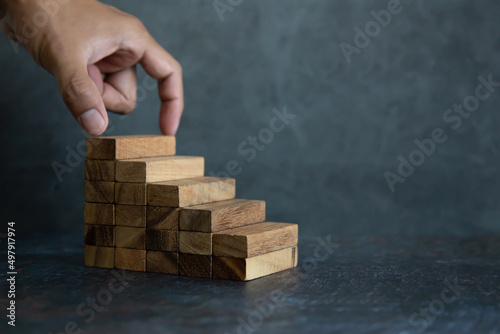 Hand place wooden block stack in pyramid stair step concept of prevent collapse or crash of financial business and risk management or strategic planning and insurance.