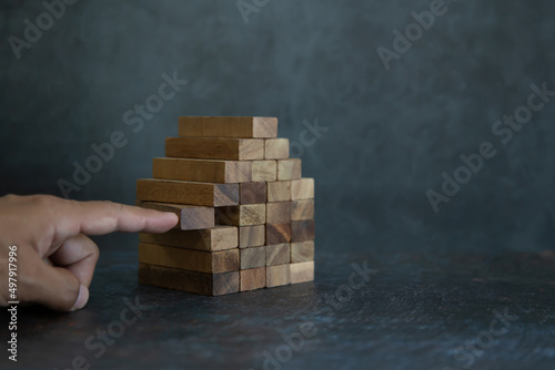 Hand place wooden block stack in pyramid stair step concept of prevent collapse or crash of financial business and risk management or strategic planning and insurance.