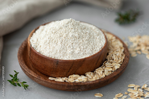 Oat wholegrain flour with oat flakes on wooden table