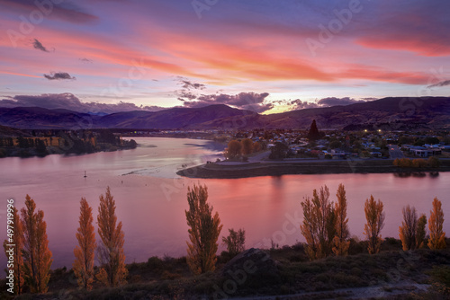 The town of Cromwell in the South Island of New Zealand, at sunset. The colorful clouds are reflected in the waters of Lake Dunstan