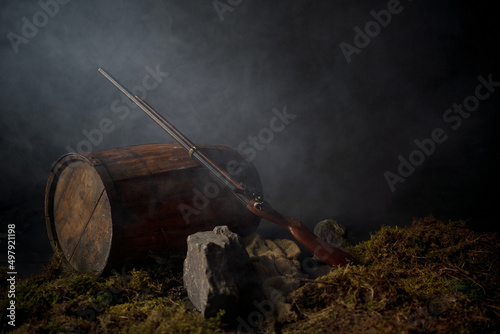 Obraz na plátně Ancient musket on a barrel among the smoke on the battlefield