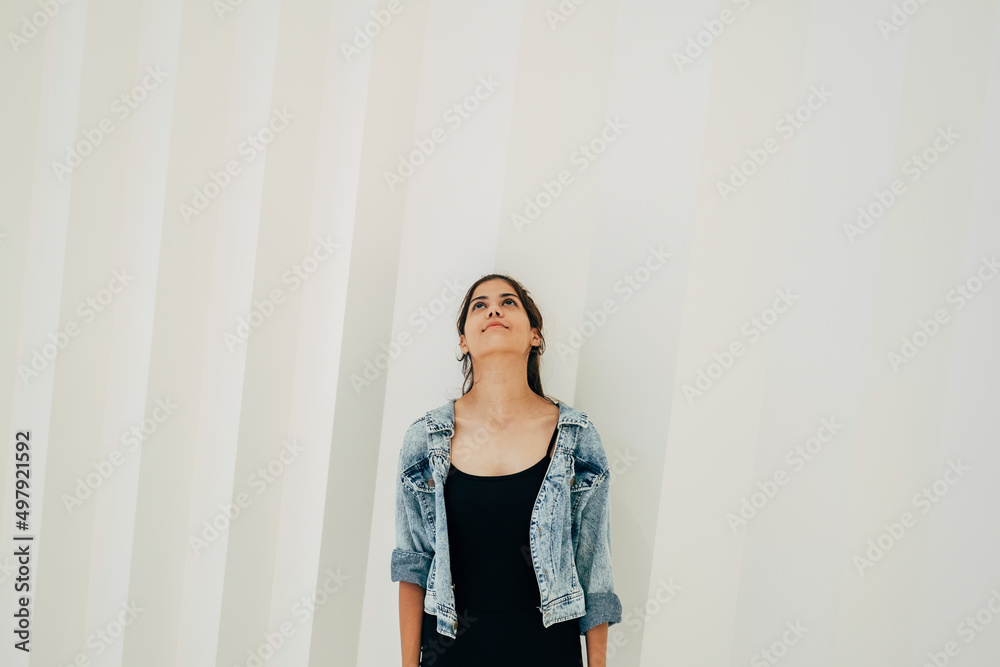 Smiling Indian Teenage Girl Standing In Front of White Background and Looking Up Curiously Smiling Indian Teenage Girl Standing In Front of White Background and Looking Up Curiously