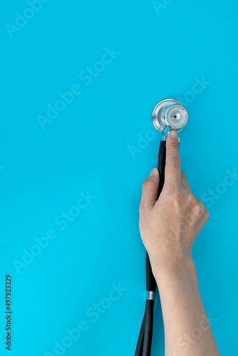 Hand holding a stethoscope on blue background