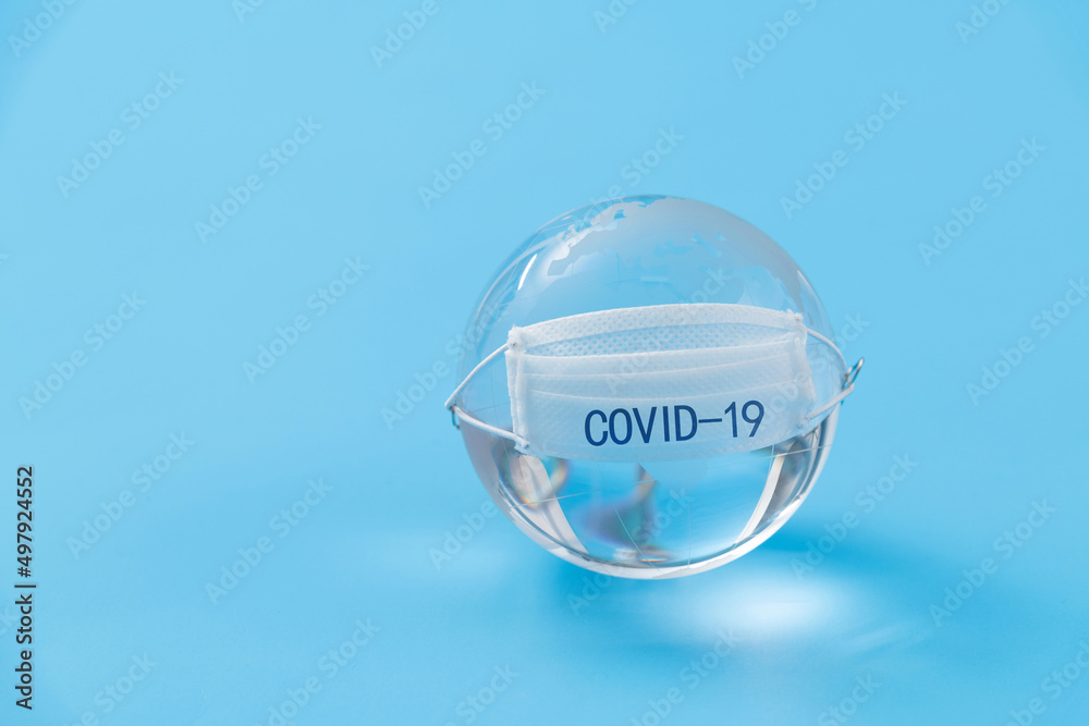 Earth globe with medical mask on blue background Earth globe with medical mask on blue background