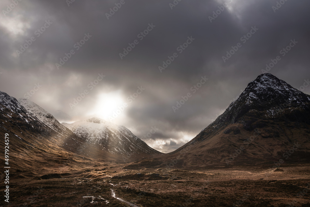 Majestic Winter landscape image of Etive Mor in Scottish Highlands with sunbeams streaming down between the mountain peaks
