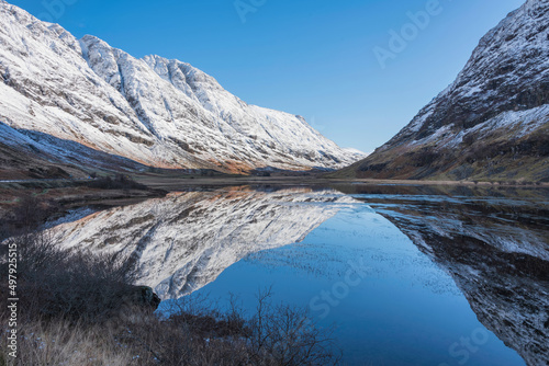 Stunning Winter landscape image of Loch Achtriochan in Scottish Highlands with stunning reflections in still water with crytal clear blue sky