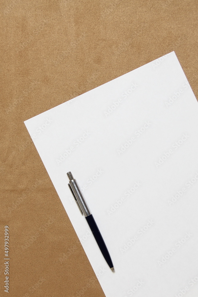 Template of white paper with pen lies diagonally on light brown cloth background. Concept of business plan and strategy. Stock photo with empty space for text and design. Template of white paper with pen lies diagonally on light brown cloth background. Concept of business plan and strategy. Stock photo with empty space for text and design.