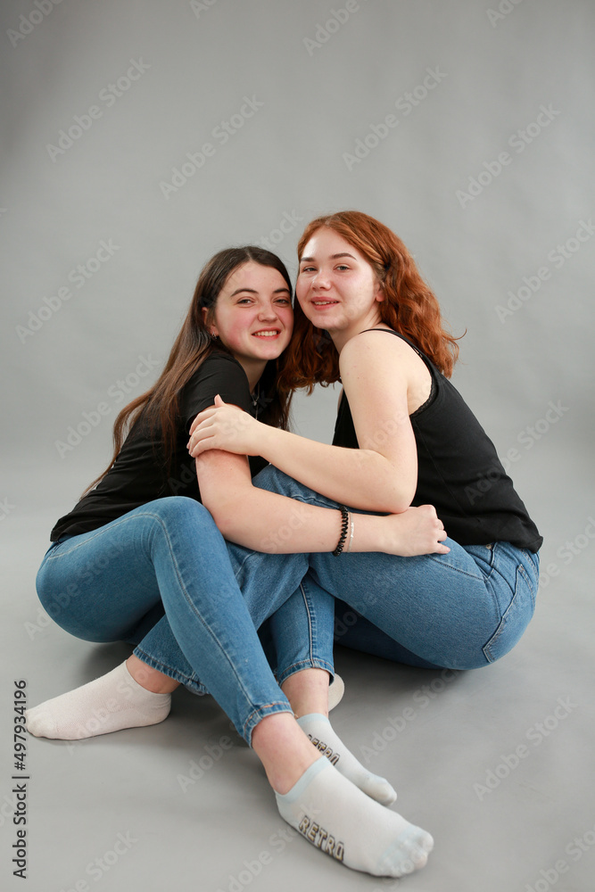 two beautiful girls on a gray background. girlfriends hugging. red hair color. studio photo shoot. female friendship. stop the war two beautiful girls on a gray background. girlfriends hugging. red hair color. studio photo shoot. female friendship. stop the war