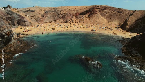Aerial view people relax on most popular Papagayo beach of Lanzarote, cove of white sand, Atlantic Ocean bay, crystal clear, green water. Travel destination and tourism concept. Canary Islands. Spain