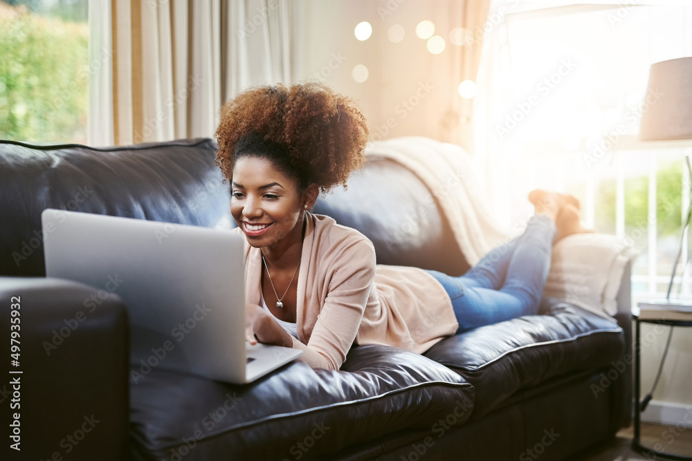 Relaxing with some online entertainment. Shot of an attractive young woman using laptop while chilling at home on the sofa. Relaxing with some online entertainment. Shot of an attractive young woman using laptop while chilling at home on the sofa.