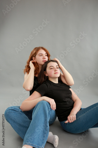 two beautiful girls on a gray background. girlfriends hugging. red hair color. studio photo shoot. female friendship. stop the war