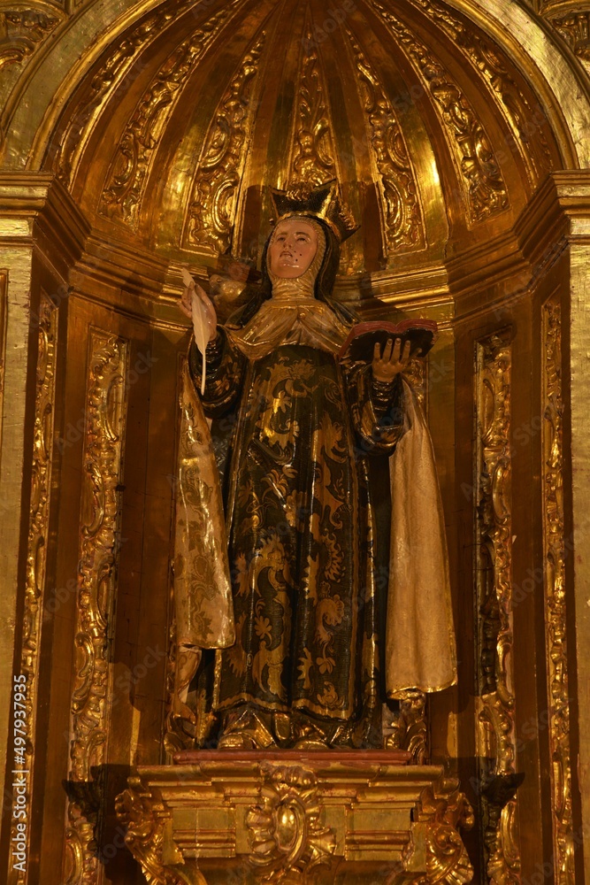 Richly embellished gilded Baroque wood sculpture of Saint Teresa of Avila, depicting the saint with her characteristic feather and book attributes at Jaen Cathedral, Jaén, Spain