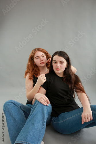 two beautiful girls on a gray background. girlfriends hugging. red hair color. studio photo shoot. female friendship. stop the war