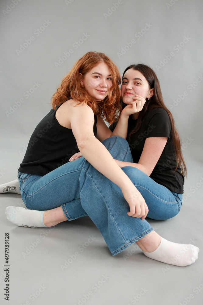 two beautiful girls on a gray background. girlfriends hugging. red hair color. studio photo shoot. female friendship. stop the war two beautiful girls on a gray background. girlfriends hugging. red hair color. studio photo shoot. female friendship. stop the war