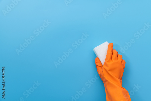 Hand holding sponge for cleaning on blue background