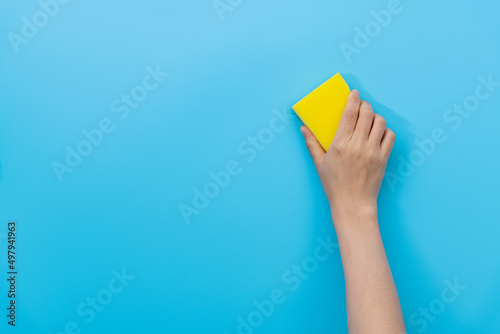 Hand holding sponge for cleaning on blue background photo