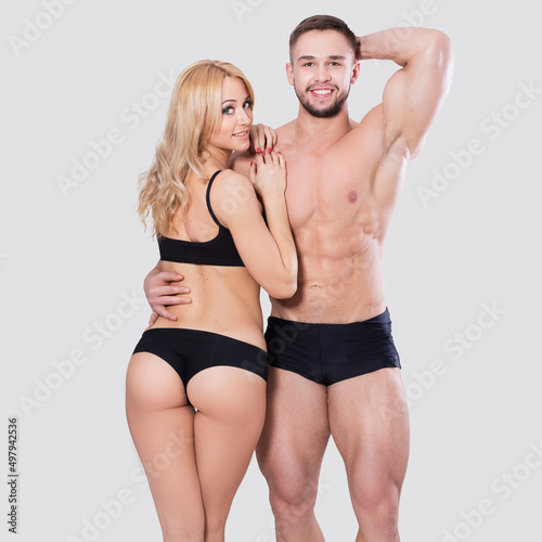 Fit couple of handsome brunette men and beutiful blond woman on grey neutral background