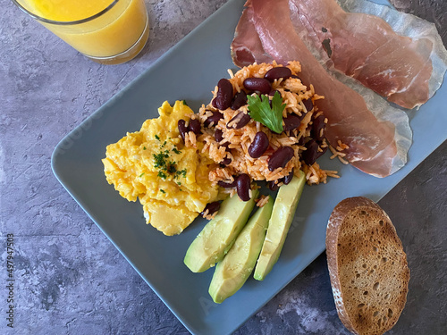 Gallo Pinto with rice and red kidney beans, served with scrambled eggs, proscuitto ham, avocado and toasted dark bread. photo